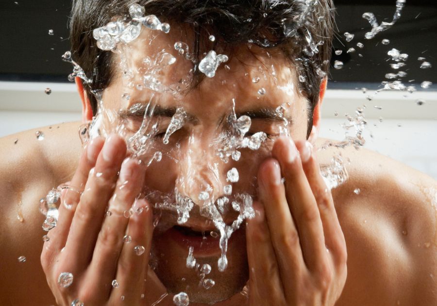 man splashing his face with cold water